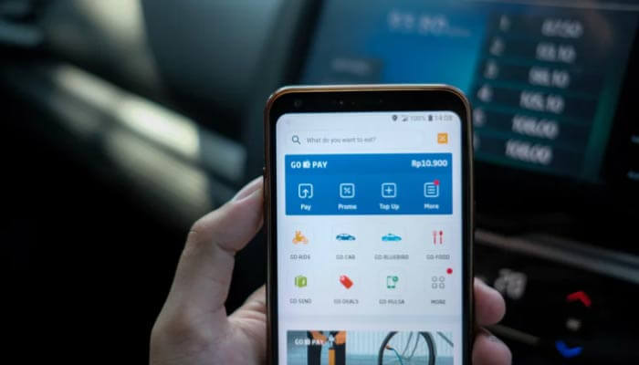 cliente verifica o Pagamento-da-corrida da uber dentro do veiculo olhando no celular