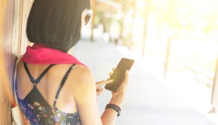 mulher encostada na parede tentando usar o celular
