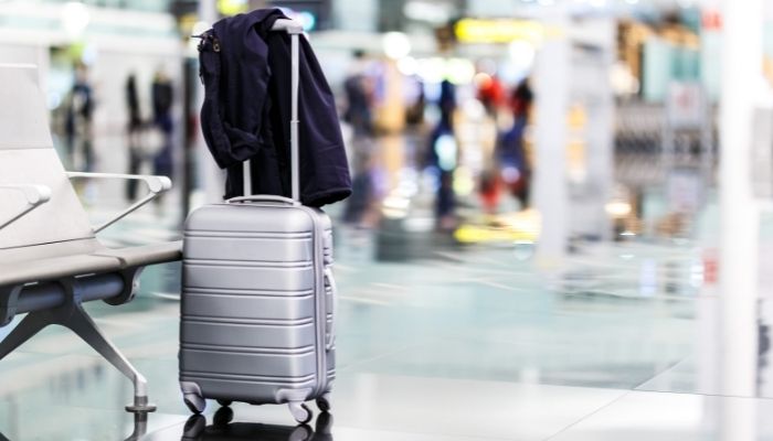 mala de vinhos no aeroporto na área de embarque com casaco por cima