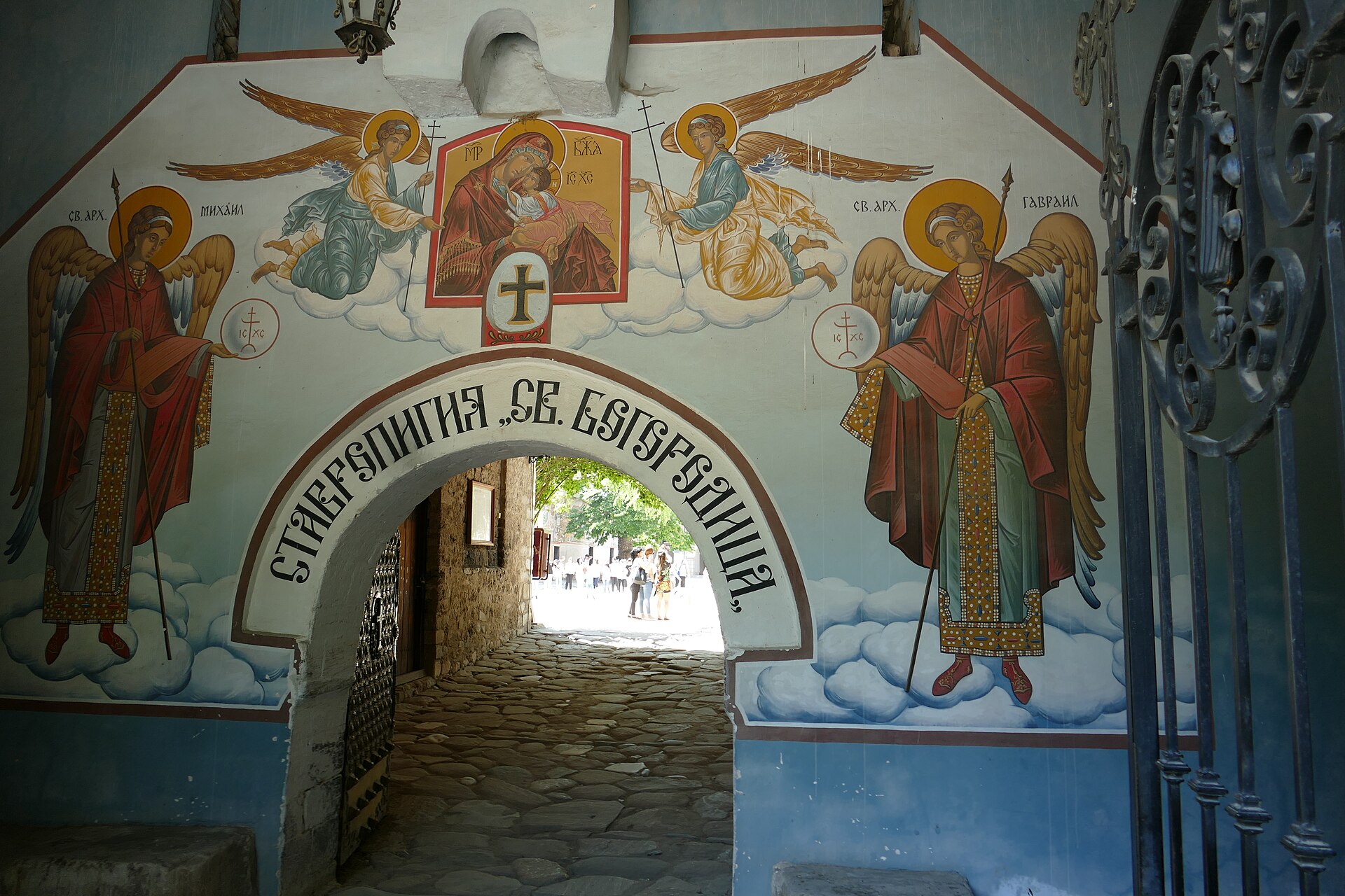 Portal em arco do Mosteiro de Bachkovo com afrescos de arcanjos e da Virgem com o Menino, e um corredor de pedra que dá para o pátio