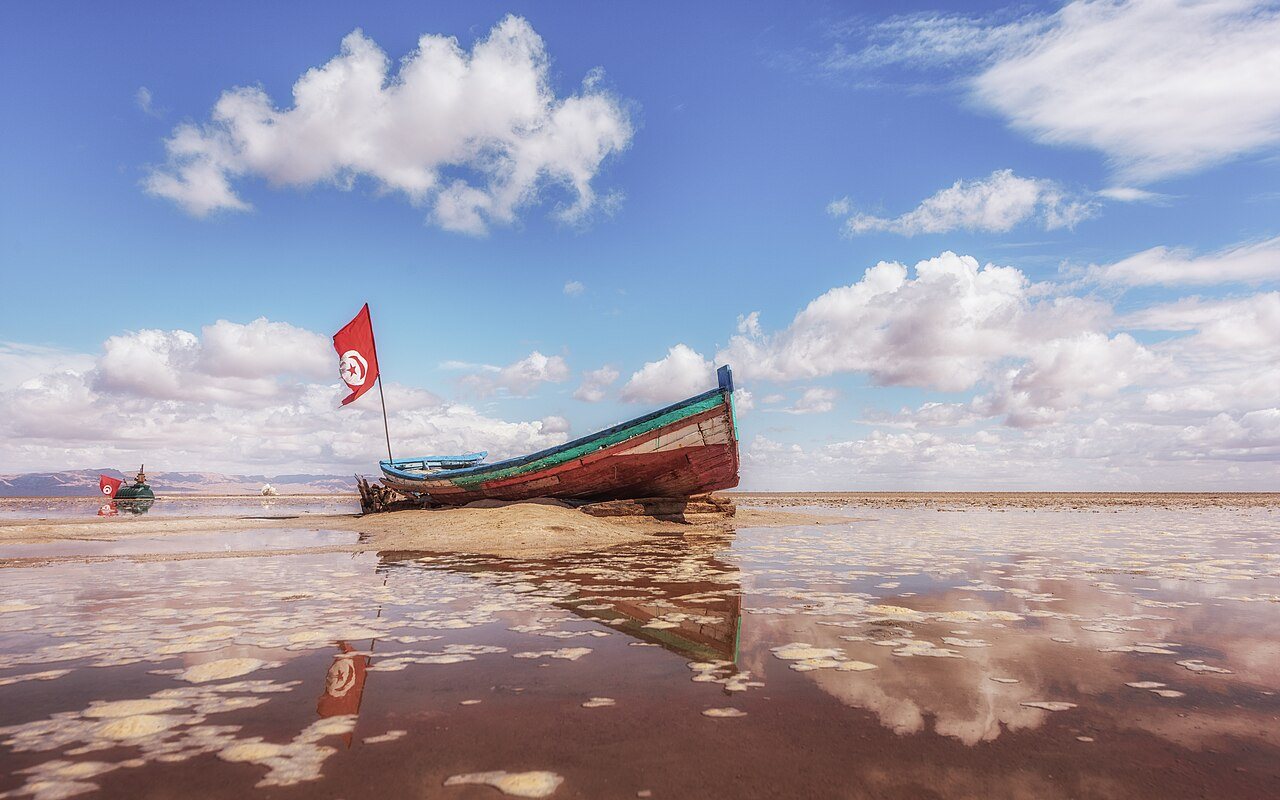 Barco parado sobre a crosta de sal do Chott el Djerid, refletido na água rasa