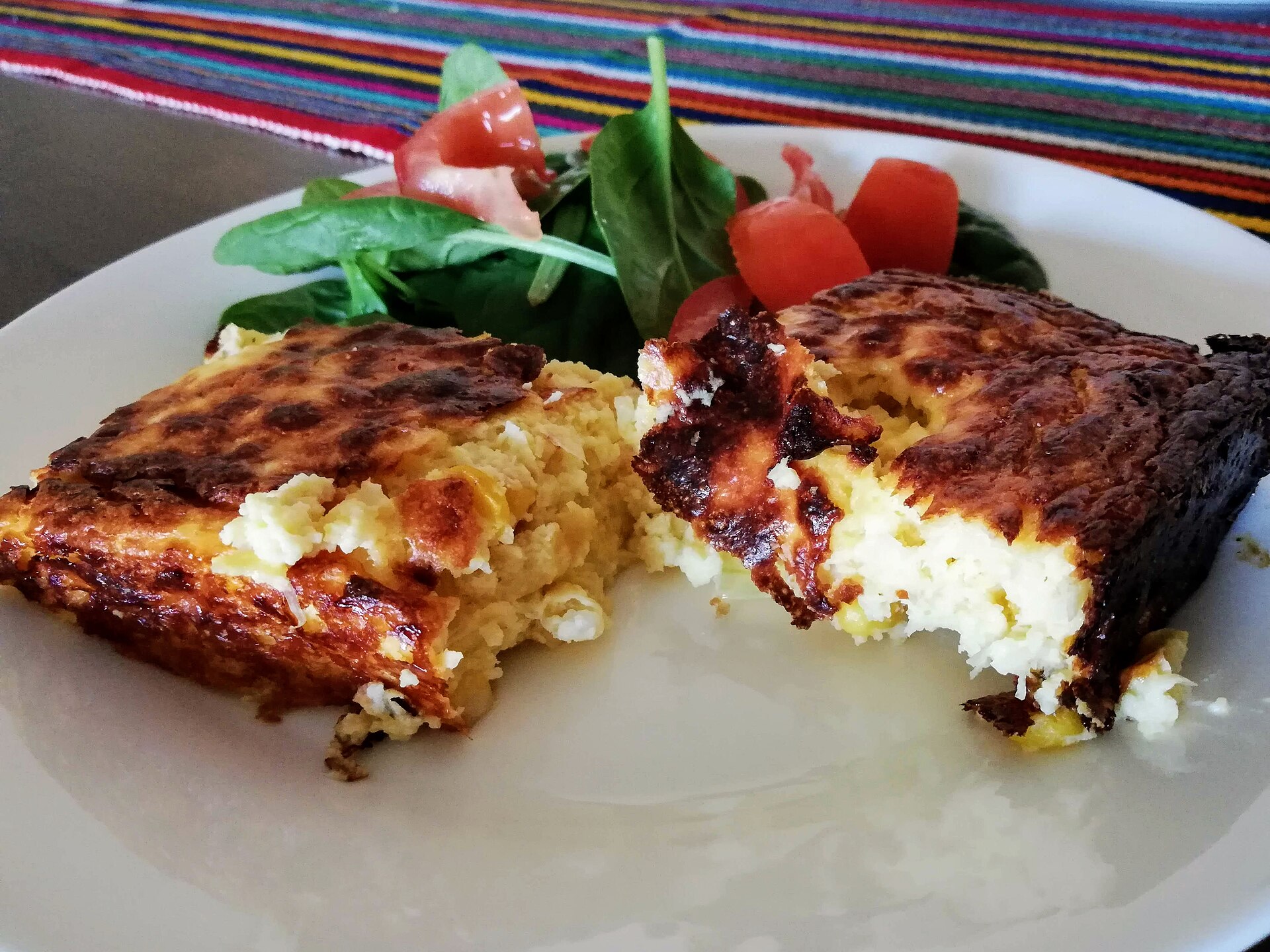 Chipa guasu servida com salada, acompanhamento típico do assado paraguaio