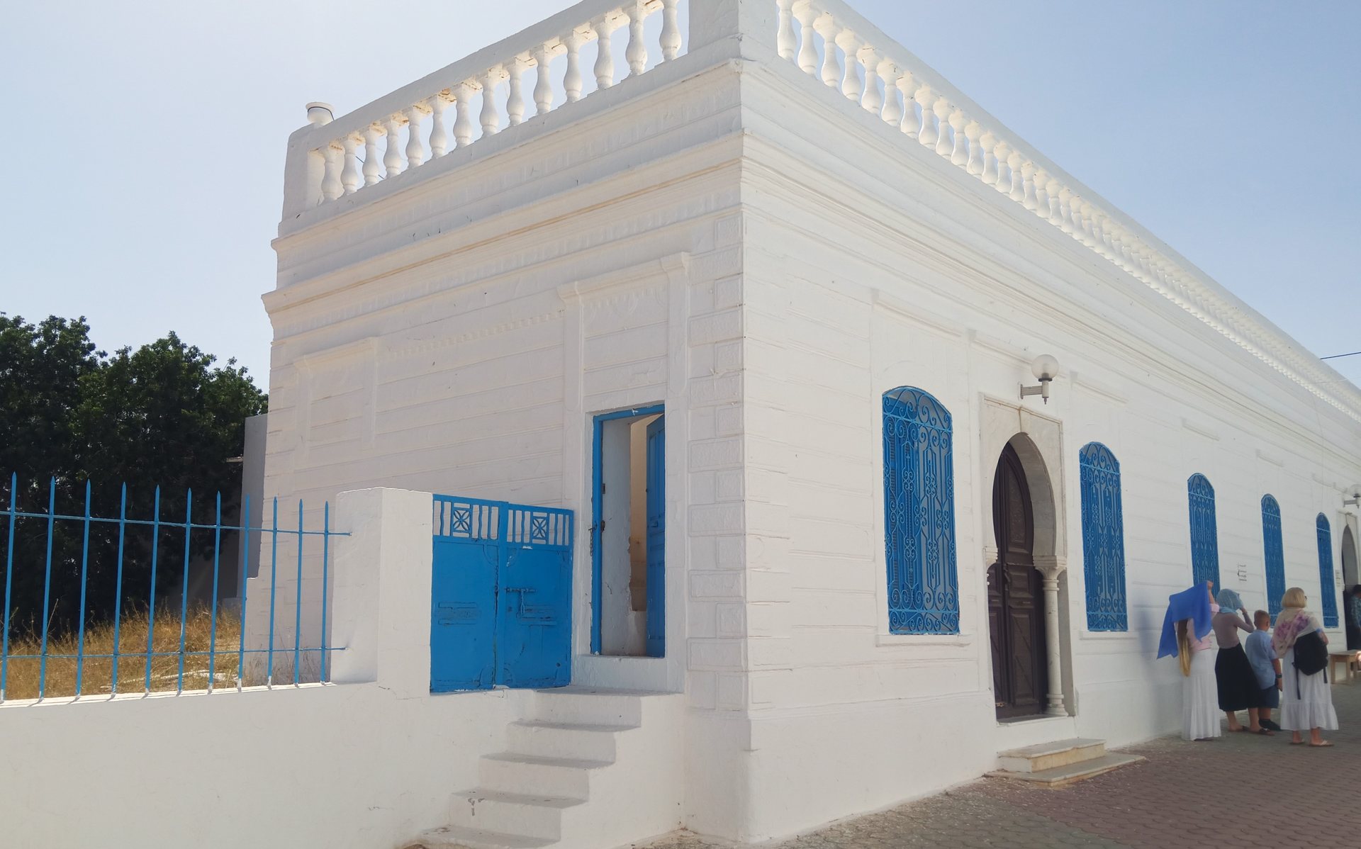 Fachada branca com janelas e grades azuis da sinagoga de El Ghriba, em Djerba