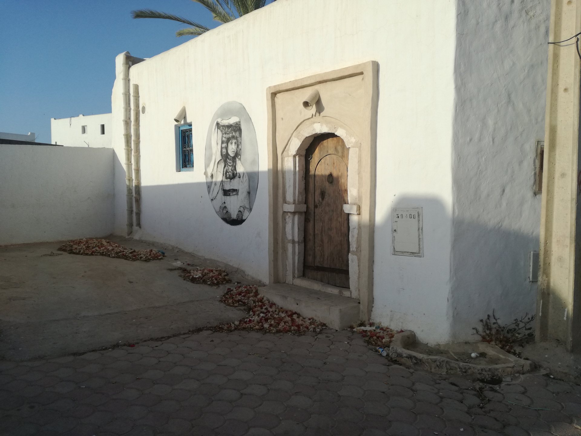 Rua de Erriadh com casa caiada e mural do projeto de arte de rua Djerbahood