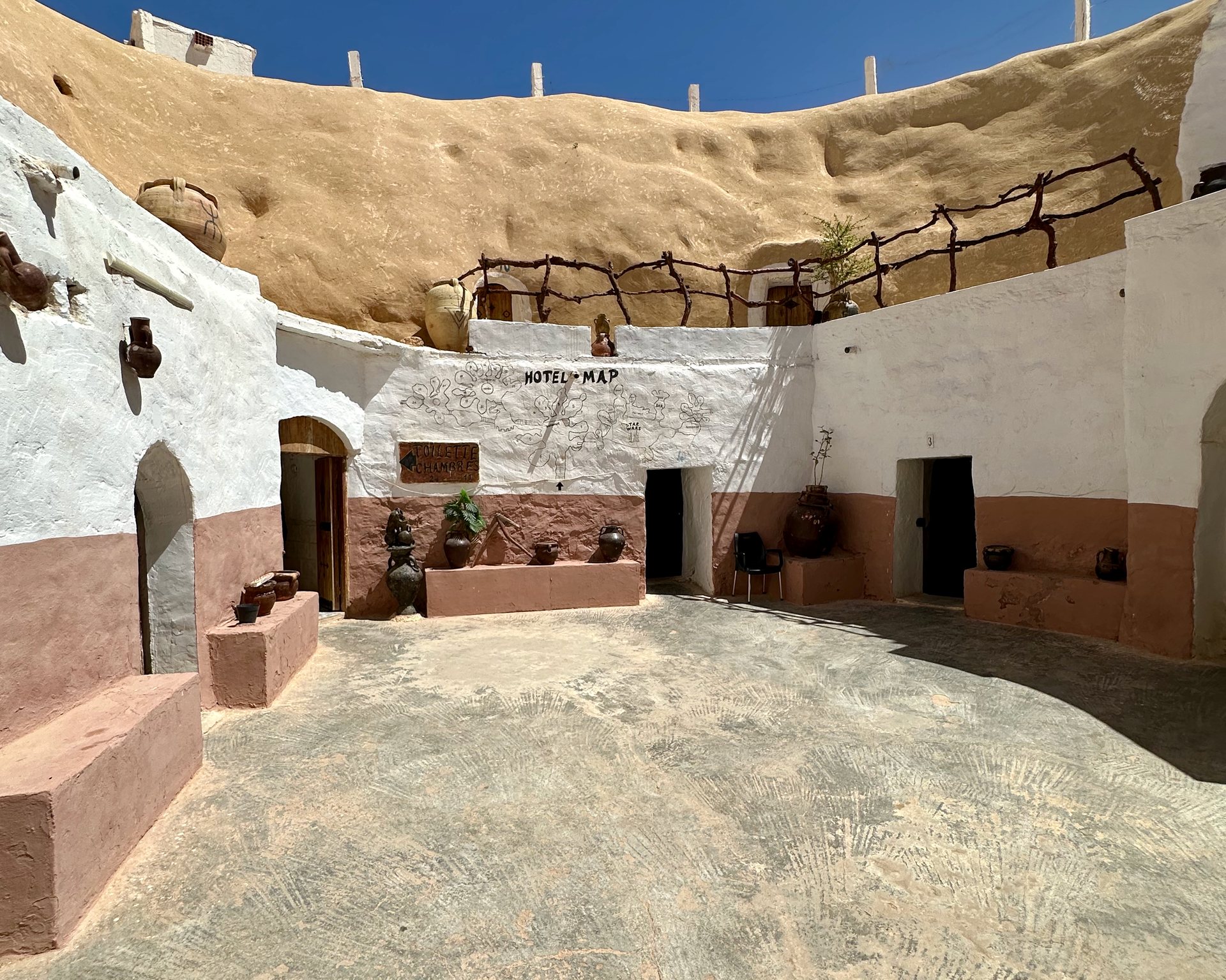 Pátio do Hotel Sidi Driss, em Matmata, com portas em arco escavadas na rocha e paredes caiadas